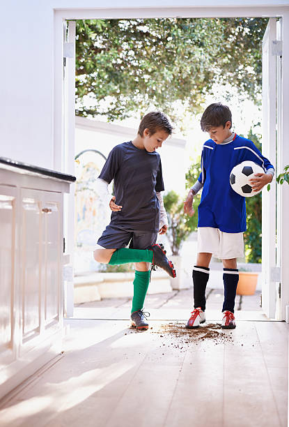 Boys will be boys Shot of two boys bringing dirt into the house after soccer practice kids dirty shoes stock pictures, royalty-free photos & images