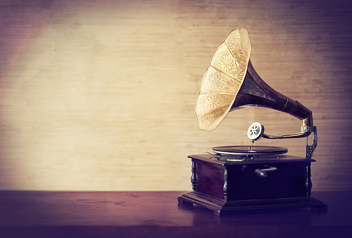 Analog vinyl record player with disc on white table. Modern turntable audio equipment.