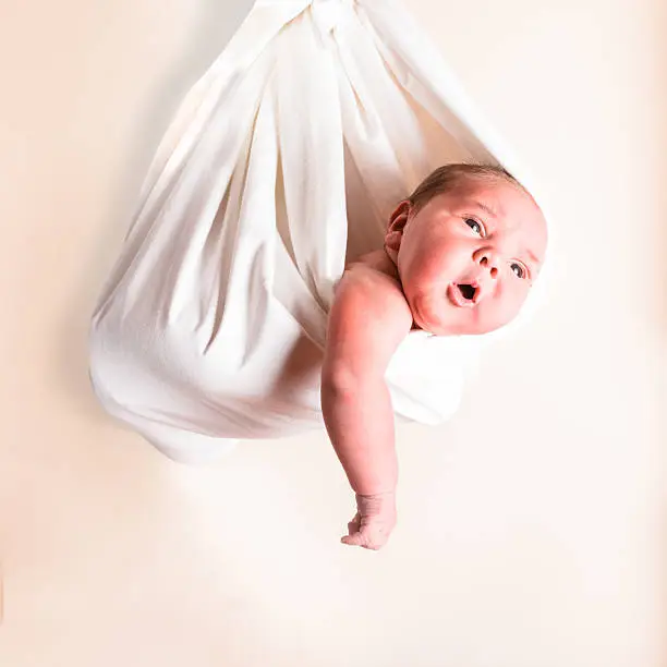 Portrait of a newborn baby in a white hammock or sling