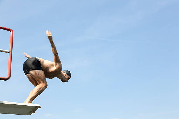 istock Man jumping off diving board at swimming pool 511390765