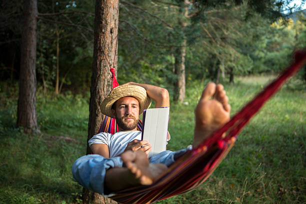 Student on hammock using digital tablet http://www.mediafire.com/convkey/6d6b/7mean2vh9anb8s3fg.jpg hammock men lying down digital tablet stock pictures, royalty-free photos & images