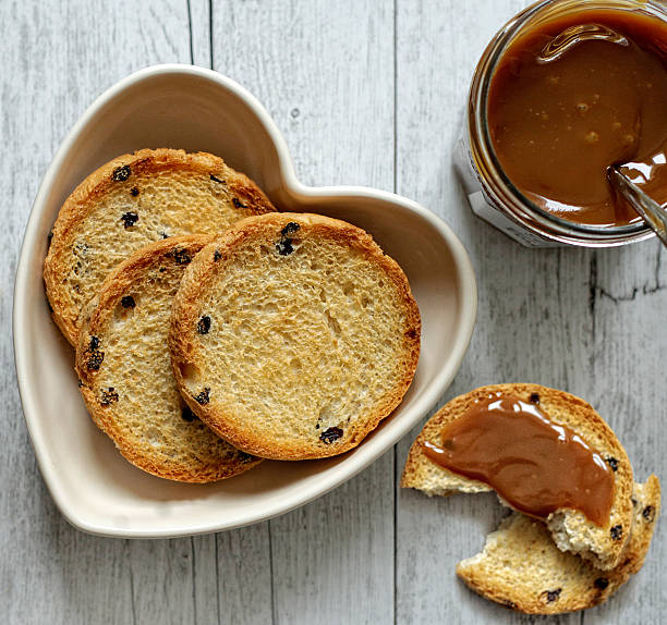 Rusks with milk jam in a heart shaped bowl stock photo