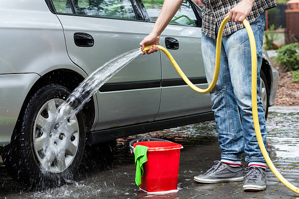Man cleaning car Man cleaning car in front of house garden hose photos stock pictures, royalty-free photos & images