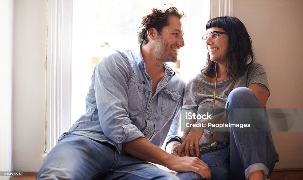 I see the whole world in your eyes... A happy couple sitting together in front of a window in their home 30-39 Years Stock Photo