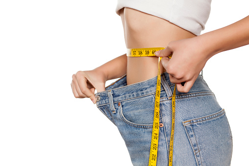 woman posing with a measuring tape and a big size pants