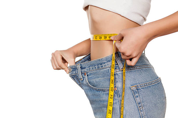 weight loss woman posing with a measuring tape and a big size pants loss photos stock pictures, royalty-free photos & images