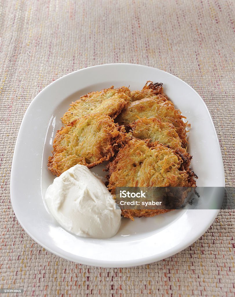 Potato pancakes with sour cream on a plate Potato pancakes with sour cream on white plate Crockery Stock Photo