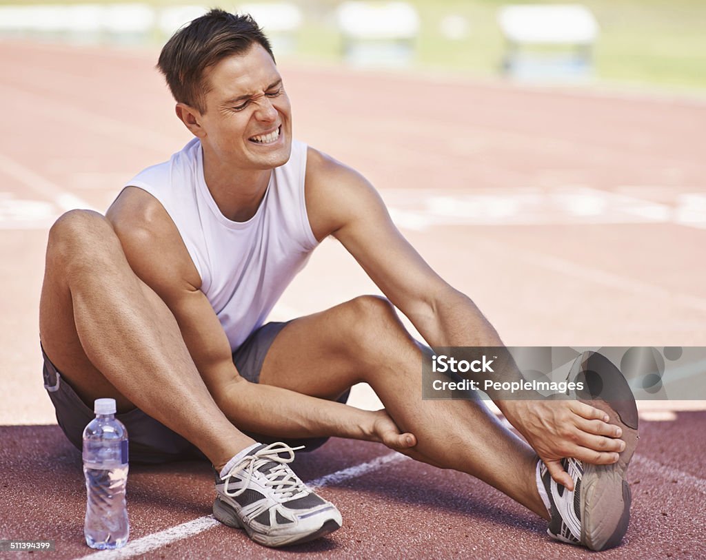 Success can be a pain Shot of an athlete feeling the pain of a strained muscle Cramp Stock Photo