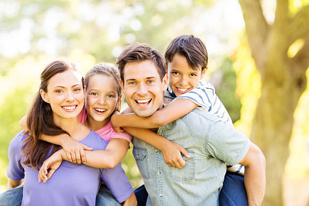 istock Playful Kids Enjoying Piggyback Ride On Parents 511435543
