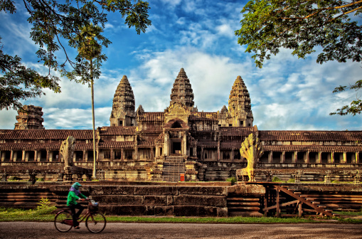 Morning shot of a local Cambodian riding a bike at the Khmer temple of Angkor Wat.