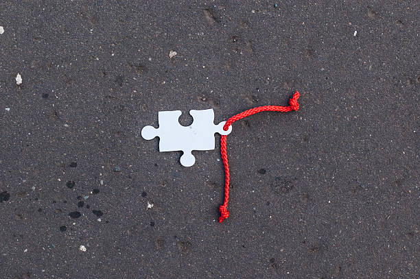 istock Missing jigsaw piece with red lace laying on tarmac 511436947