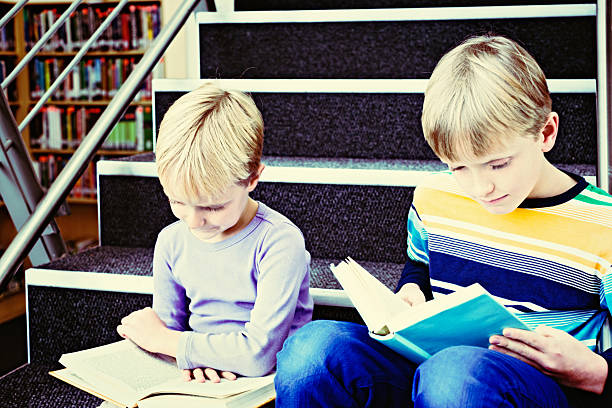 istock Contented brother and sister reading on library stairs 511438461