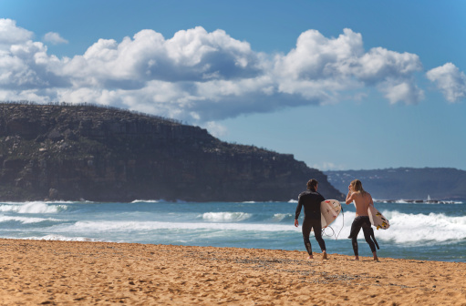 Palm Beach,Australia - August 31, 2014: Two men walk along the beach after surfing. Australia has some of the world's best surfing spots.