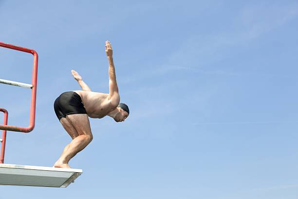 istock Man jumping off diving board at swimming pool 511443139
