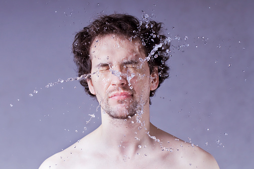 Handsome man with splashing water on his face.