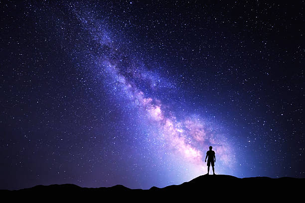 istock Milky Way. Night sky and silhouette of a standing man 511459456