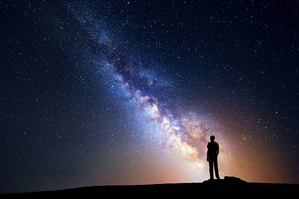 istock Milky Way. Night sky and silhouette of a standing man 511459498