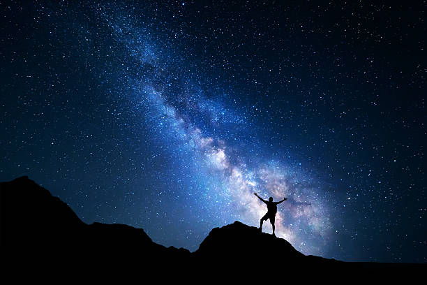 istock Milky Way. Night sky and silhouette of a standing man 511459582
