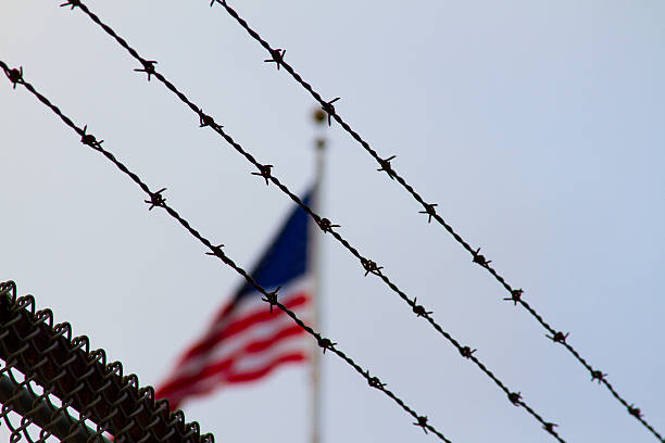 American Flag Behind Barb Wire An American flag behind a barbwire fence. May symbolize prison, political messages, or loss of freedom. concentration camp photos stock pictures, royalty-free photos & images