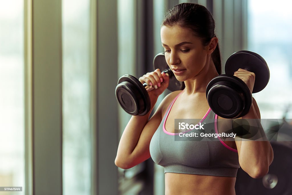 Woman in gym Attractive young woman working out with dumbbells in gym Women Stock Photo