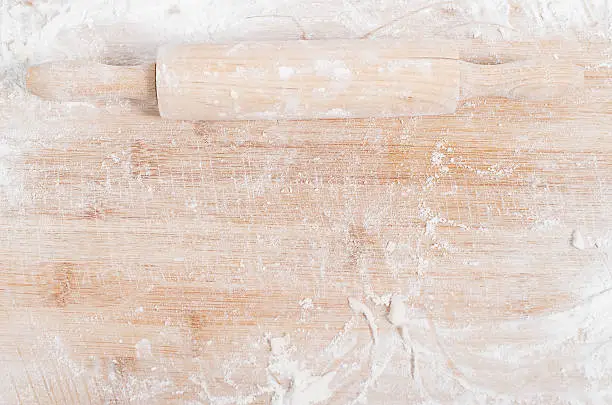 Photo of Rolling pin on a wooden tray covered with flour