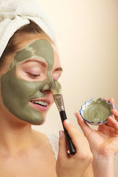 istock Woman applying with brush clay mud mask to her face 511465514