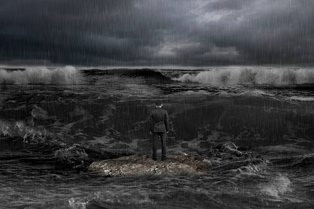 istock businessman standing on rock facing oncoming waves with dark oce 511466732
