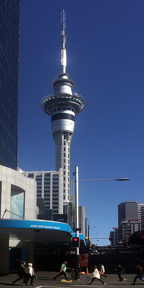 Auckland, New Zealand - September 12, 2015: Padestrians walk on Queen street with the Skytower in the background. It's a major commercial thoroughfare in the Auckland CBD, New Zealand's main population center.