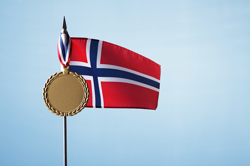 Norwegian flag with gold medal against blue sky