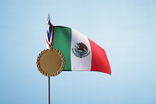 Mexican flag with gold medal against blue sky