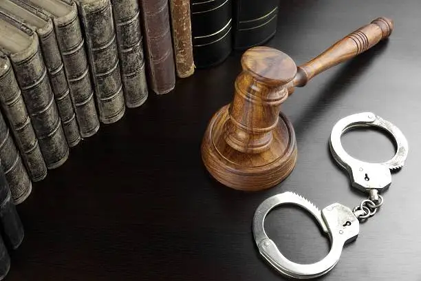 Judges Gavel, Handcuffs And Old Law Book  On The Black Wooden Table Background In The Back Light. Overhead View. Lawsuit or Bail Or Arrest Concept