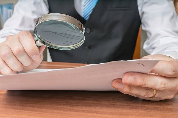 istock Businessman is inspecting contract with magnifying glass. 511473084
