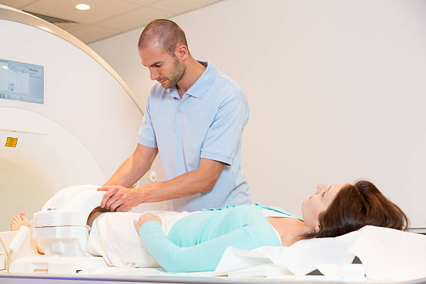 Medical technical assistant preparing scan of knee with MRI Medical technical assistant councelling patient and preparing scan of the knee with magnetic resonance tomography MRI in radiology human knee stock pictures, royalty-free photos & images