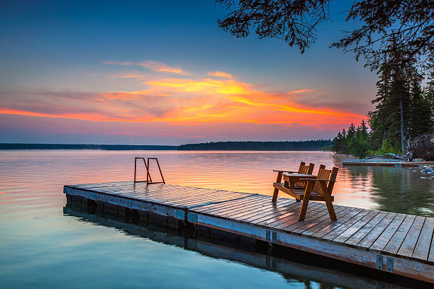 Sunrise over the dock in Clear Lake, Manitoba Bench sitting on the dock as a colourful sunrise lights up the sky over Clear Lake, in Riding Mountain National Park, Manitoba Canada manitoba photos stock pictures, royalty-free photos & images
