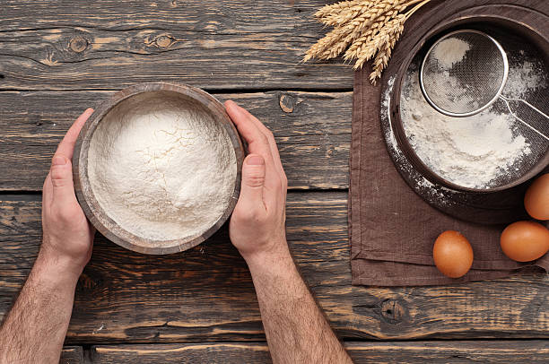 istock Baker holds a wooden bowl with flour powder 511473694