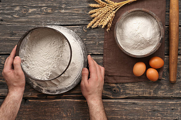 istock baker sift the flour on a dark rustic wooden background 511473742