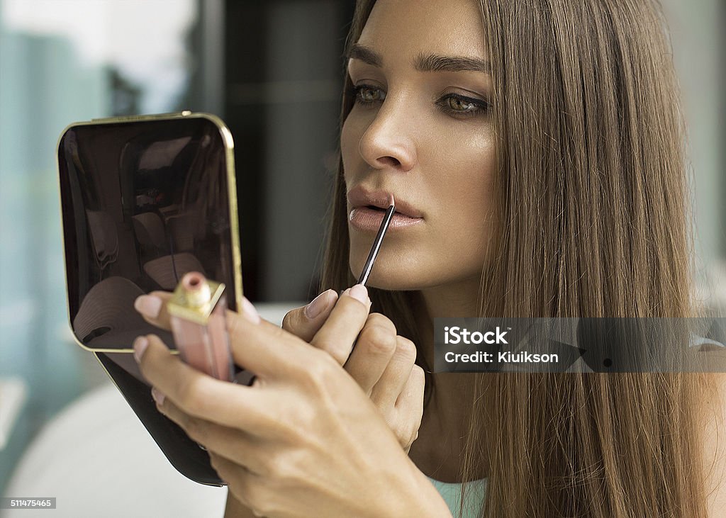 Woman putting lipstick and looking in mirror Looking Stock Photo