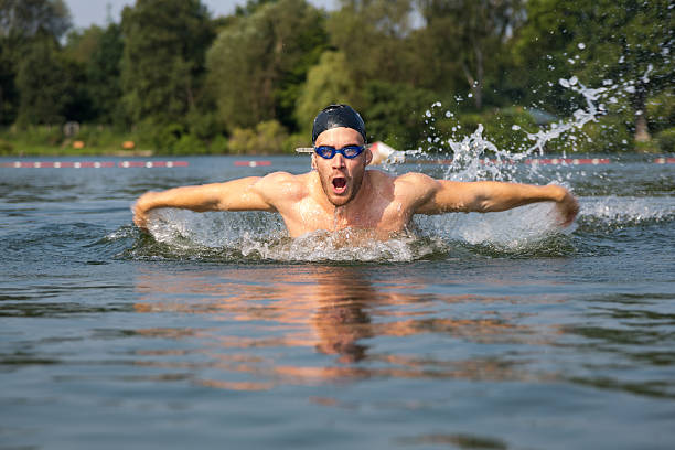 Professional triathlete swimming in river's open water. Man wearing swim equipment practicing triathlon on the beach in summer's day. Concept of healthy lifestyle, sport, action, motion and movement.