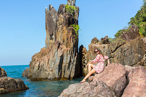 istock Beautiful woman sitting on rocks sea coast. 511476468