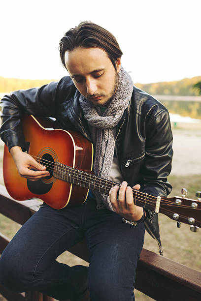 istock Young man playing on guitar at the lake 511476760