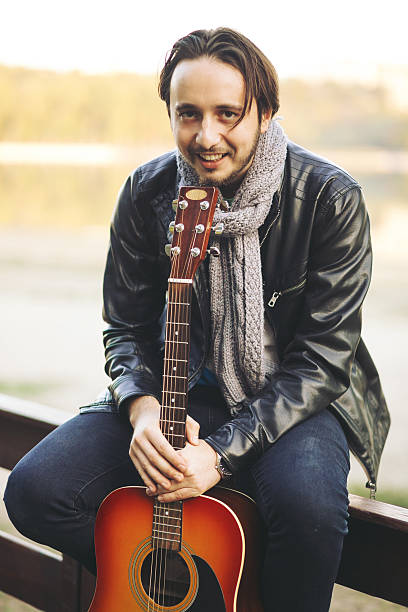istock Young man playing on guitar at the lake 511476842
