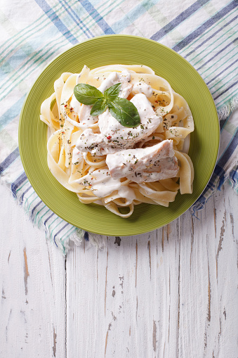 alfredo pasta in cream sauce with chicken on a plate. vertical top view