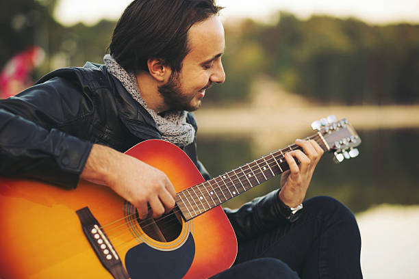 istock Young man playing on guitar at the lake 511477102