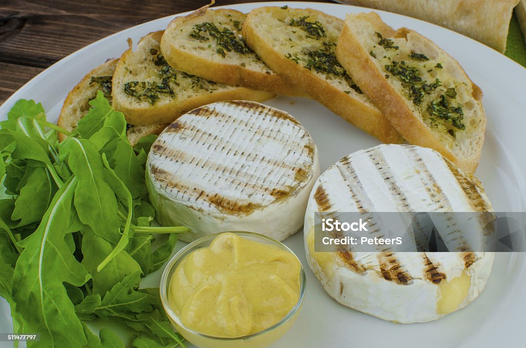 Grilled camembert with baguette Grilled camembert with baguette and mustard with arugula salad Appetizer Stock Photo