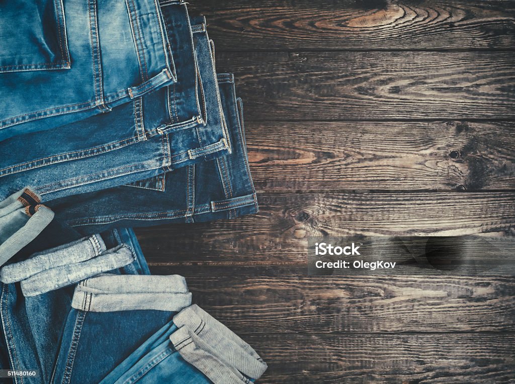 Blue jeans on a brown wooden background. Blue jeans on a brown wooden background.Frayed jeans on a rough wood surface. Denim Stock Photo