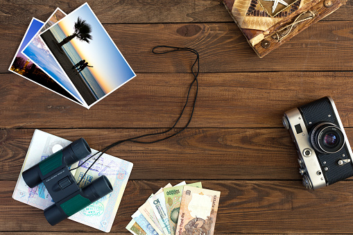 Travel Memories Vintage Composition with old Camera exotic Countries Currency Notes handmade Travel Book Binoculars and opened Passport with many visas and entry stamps Colour Photos on Hardwood Background