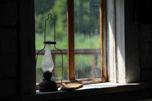 Old lamp on the window sill in a  dusty old village house in Ukraine