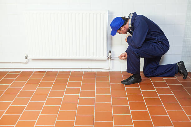 istock Handyman in blue boiler suit repairing a radiator 511503745