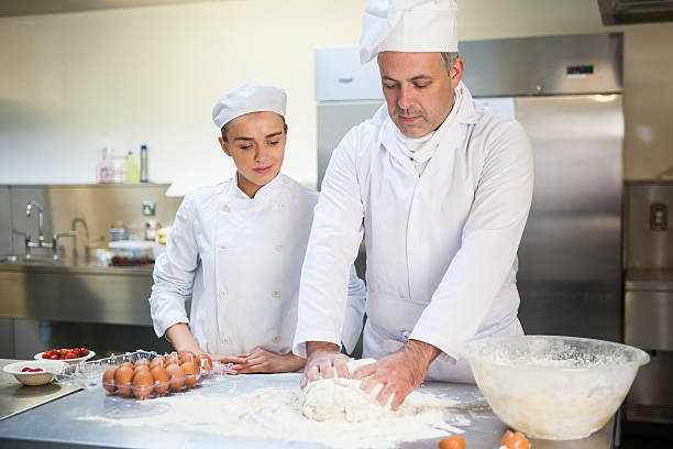 istock Head chef showing trainee how to prepare dough 511503823