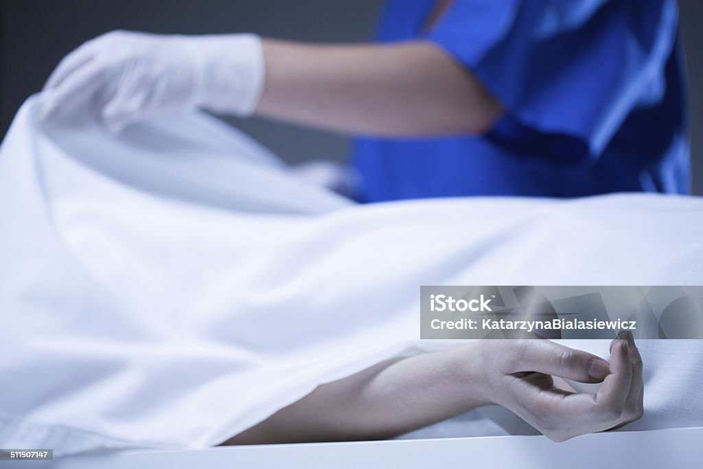 Corpse covered by sheet Worker of morgue covering corpse by sheet Dead Person Stock Photo